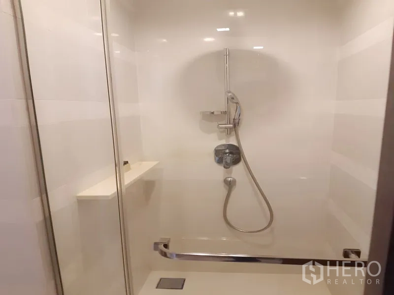 公寓 出租在Khlong Toei, Bangkok - 玻璃淋浴间，手持花洒与白色墙砖。