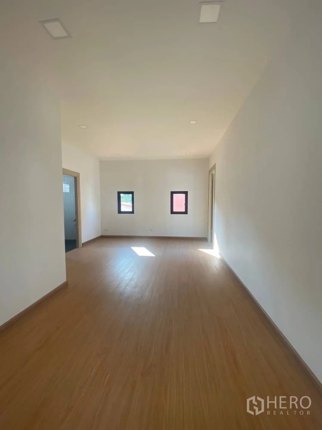 Home Office for sale - Large multipurpose room with warm flooring and natural light from small windows.