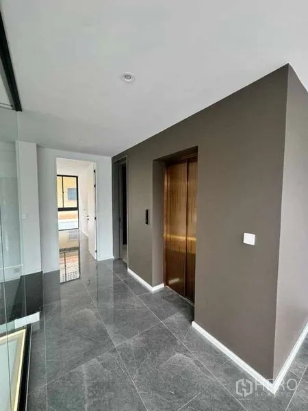 สำนักงานที่บ้าน ให้เช่าหรือขายในLat Phrao, Bangkok - โถงทางเดินสว่างพร้อมลิฟต์ส่วนตัวสีทองและพื้นหินอ่อนสีเทาเงางาม.