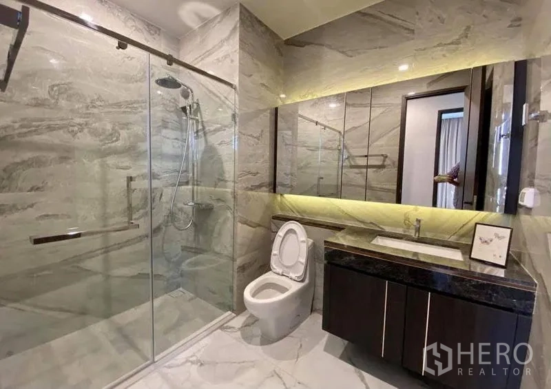 Condominium for rent in Watthana, Bangkok - Second bathroom with large glass-enclosed shower, backlit mirror and marble tiles.
