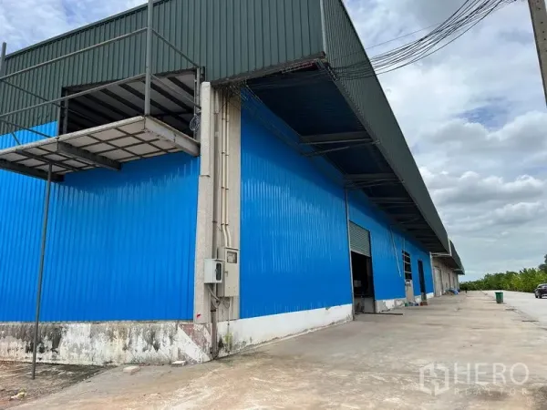 Warehouse for rent in Lat Krabang, Bangkok - Blue metal-clad warehouse exterior with covered loading bays and a wide concrete yard.