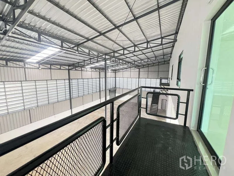 คลังสินค้า ให้เช่าหรือขาย - ระเบียงชั้นลอยมองเห็นพื้นที่โกดัง พร้อมราวกันตกเหล็กและโครงหลังคา