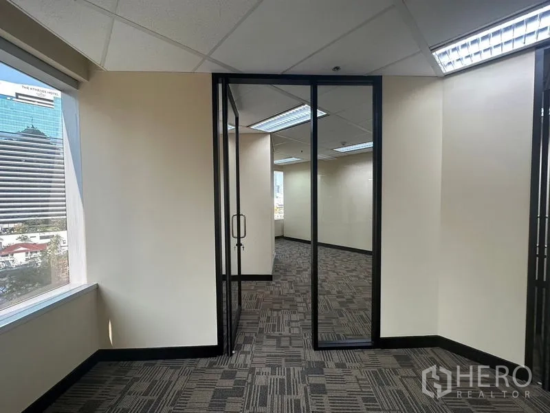 办公空间 出租 - 转角办公区，带窗与玻璃门，可见曼谷天际线景观。