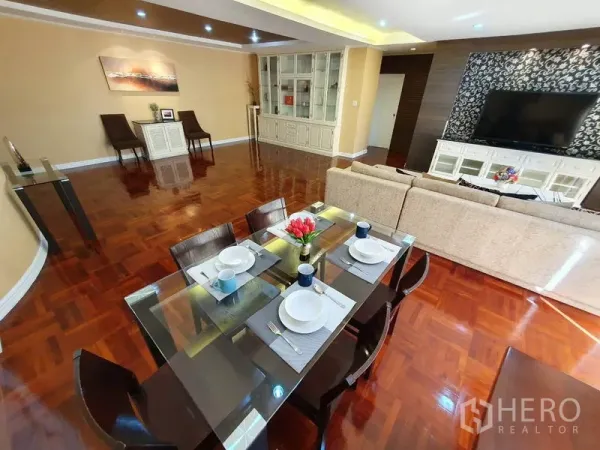 Condominium for rent in Watthana, Bangkok - Glass-top dining table set beside TV feature wall and built-in storage.