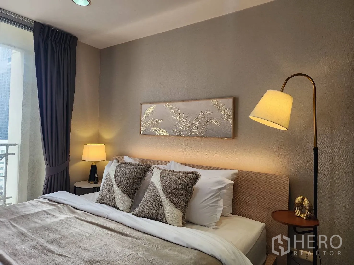 Condominium for rent in Watthana, Bangkok - Close-up of bed headboard with standing lamp, artwork and nightstand.