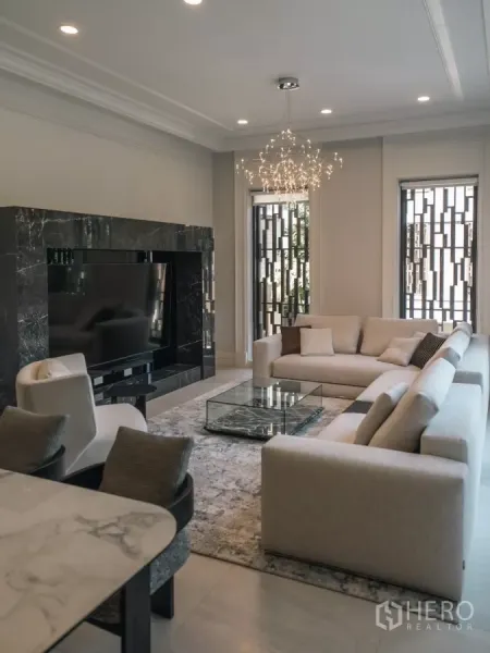 บ้าน ให้เช่าหรือขายในBang Kapi, Bangkok - ห้องนั่งเล่นหรู โซฟาสีครีม ผนังหินอ่อน ทีวี และโคมแชนเดอเลียร์