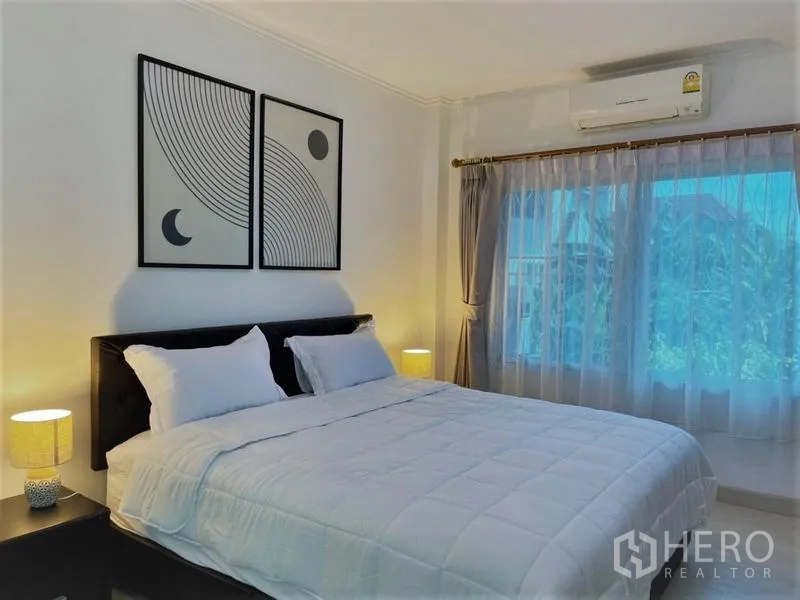 บ้าน ให้เช่าในSuan Luang, Bangkok - มุมห้องนอนหลักอบอุ่น โชว์เตียง ศิลปะติดผนัง และโคมไฟหัวเตียง.