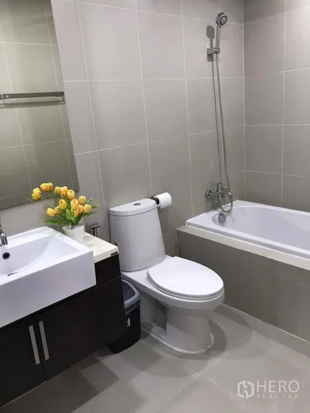 公寓 出租在Khlong Toei, Bangkok - 现代浴室，浴缸、花洒、洗手台与中性瓷砖。