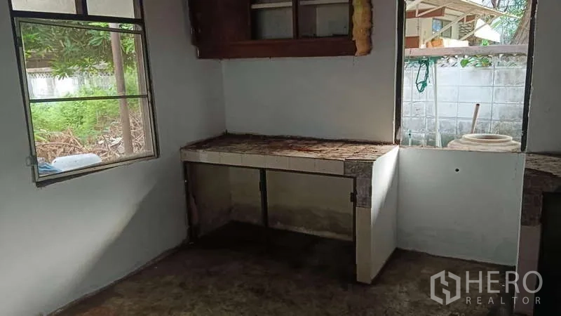 ทาวน์เฮาส์ ให้เช่า - มุมครัวพื้นฐานมีเคาน์เตอร์บิวท์อินและหน้าต่างสองบานมองเห็นต้นไม้