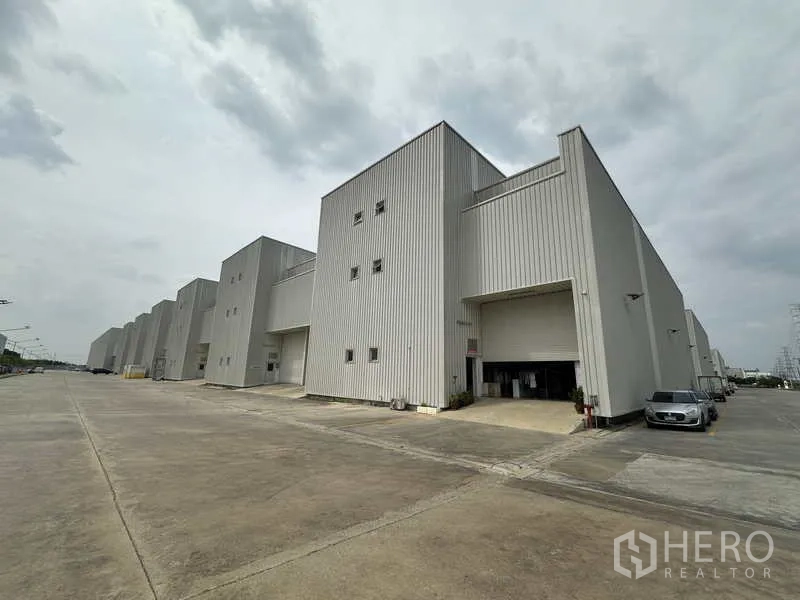 Factory for rent in Khlong Luang, Pathum Thani - Row of modern high-bay factory buildings with wide truck-friendly driveway and loading bays.