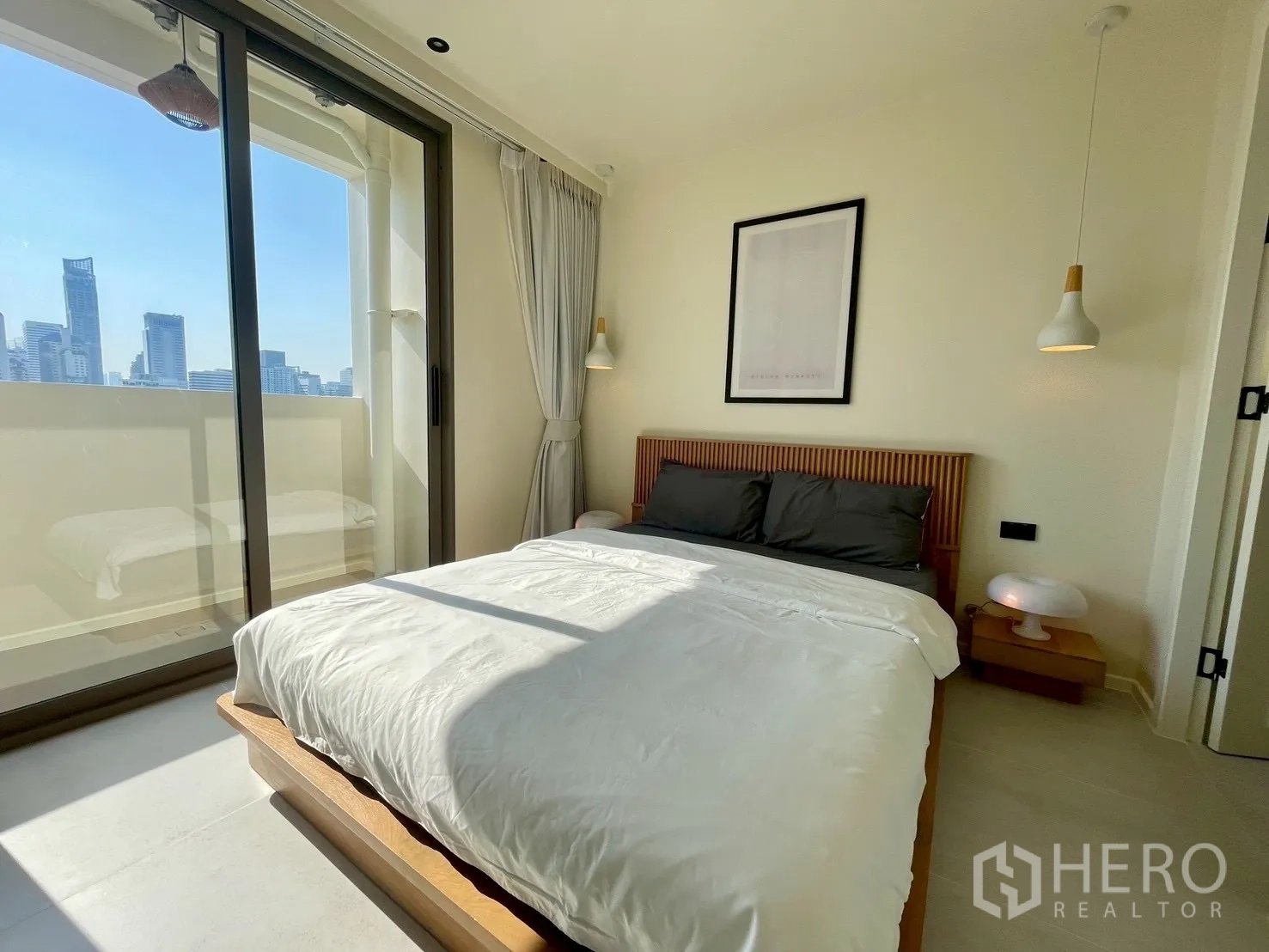 Condominium for sale in Watthana, Bangkok - Bedroom with sliding glass doors to balcony and panoramic city view.
