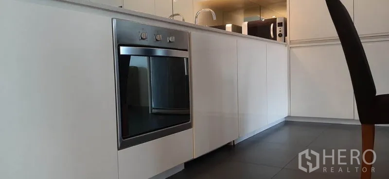 คอนโด ให้เช่าในPhaya Thai, Bangkok - ภาพระยะใกล้เตาอบบิวท์อินสแตนเลสและตู้บานสีขาวในครัวโมเดิร์น