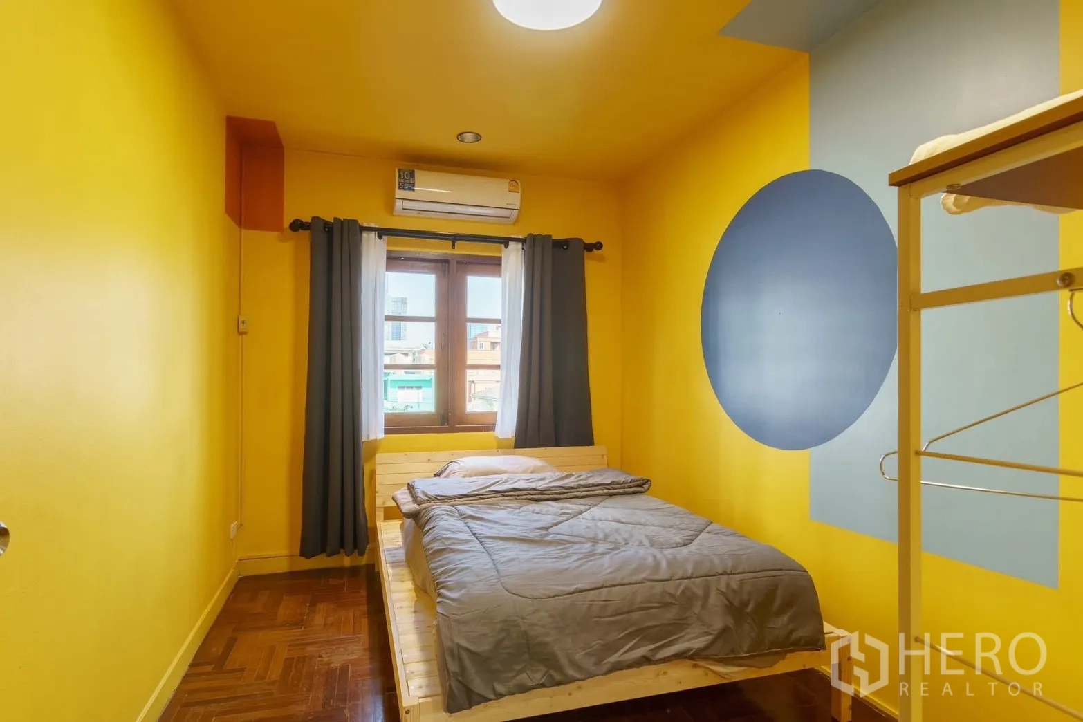 联排别墅 for rent in Watthana, Bangkok - 黄色卧室，双人床、窗帘与壁挂空调。