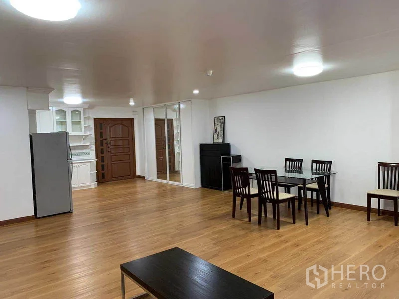 คอนโด ให้เช่าหรือขายในWatthana, Bangkok - พื้นที่นั่งเล่นเปิดโล่ง ชุดโต๊ะทานข้าว ผนังกระจกเงา และพื้นไม้ติดกับครัว