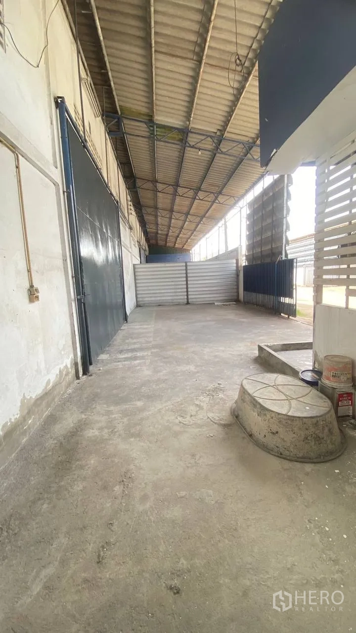 Factory for rent in Bang Phli, Samut Prakan - Covered side loading area with metal gate and large sliding factory door.