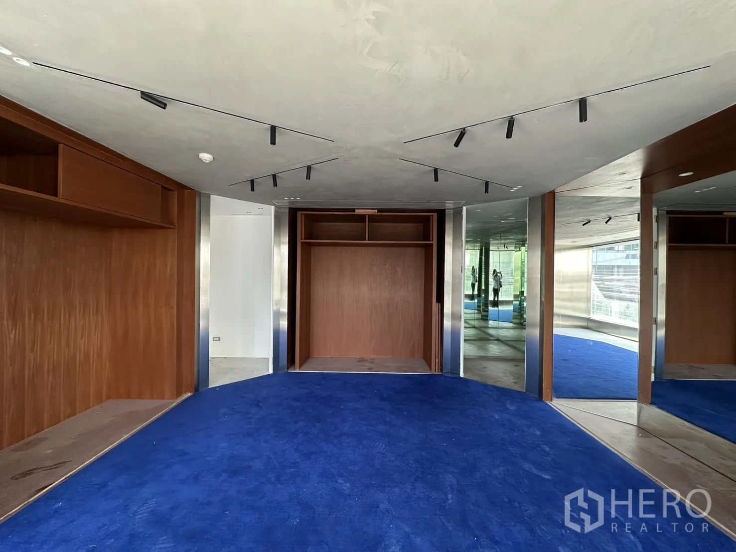 Retail Space for rent in Watthana, Bangkok - Upper showroom area with blue carpet, wood shelving, mirrors, and track lighting.