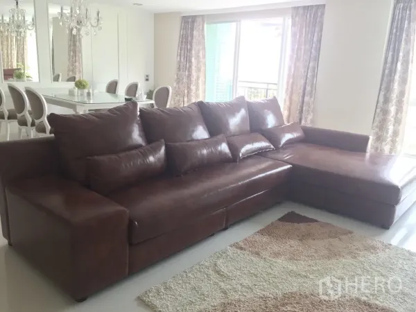 คอนโด ให้เช่าในKhlong Toei, Bangkok - ห้องนั่งเล่นสว่าง โซฟาหนังสีน้ำตาลตัวแอล กับประตูบานเลื่อนออกระเบียง