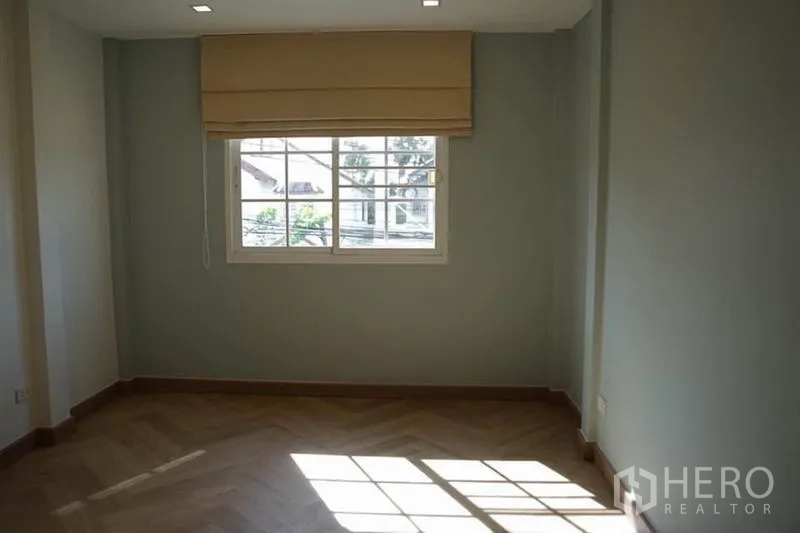 Detached House for rent in Wang Thonglang, Bangkok - Second bedroom with herringbone wood flooring and natural light from a window.