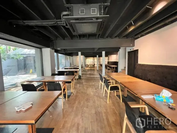 零售空间 出租在Bangkok - 长形开放式用餐大厅，木桌、黑色天花与大窗。