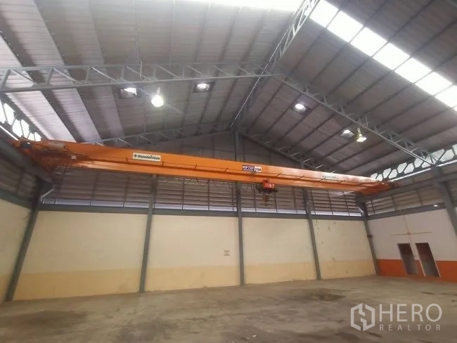 Factory for rent in Mueang Samut Sakhon, Samut Sakhon - Close-up of an orange overhead crane mounted beneath the steel roof structure.