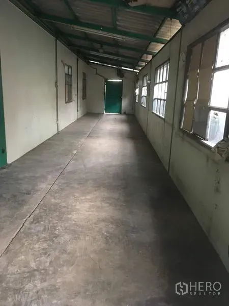 Warehouse for rent in Saphan Sung, Bangkok - Long covered corridor with windows and concrete flooring inside the warehouse complex.