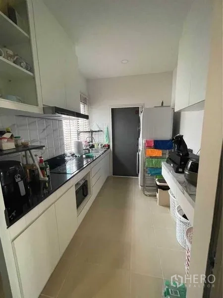 บ้าน ขายในLat Krabang, Bangkok - ครัวแคบยาวตู้สีขาว เครื่องใช้ไฟฟ้า และประตูหลังบ้าน