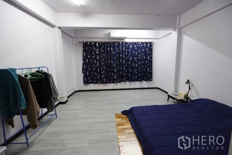 店屋 出租或出售在Watthana, Bangkok - 大卧室/工作室，灰色地面，深蓝窗帘，地铺床与衣架