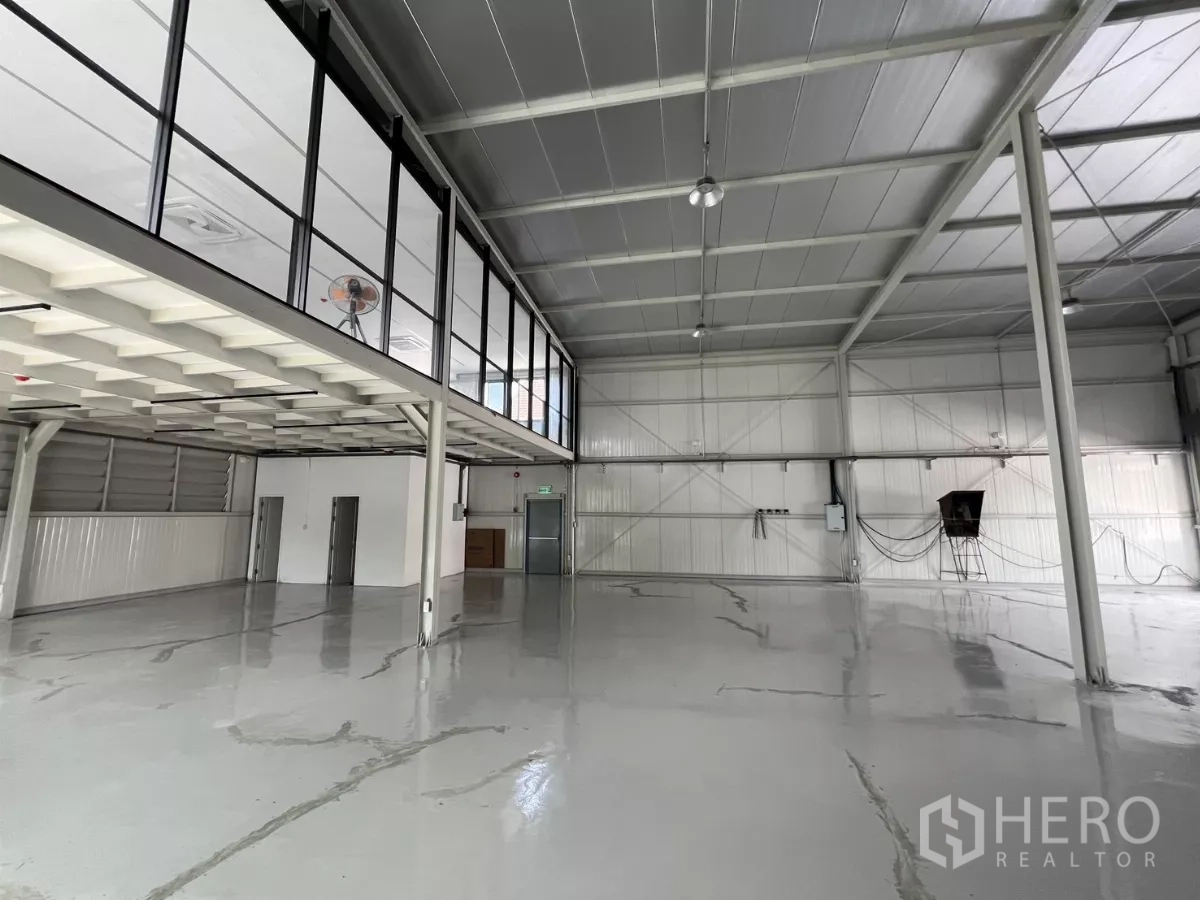 Warehouse for rent in Bang Na, Bangkok - Open storage area beneath mezzanine with polished floor and access doors.