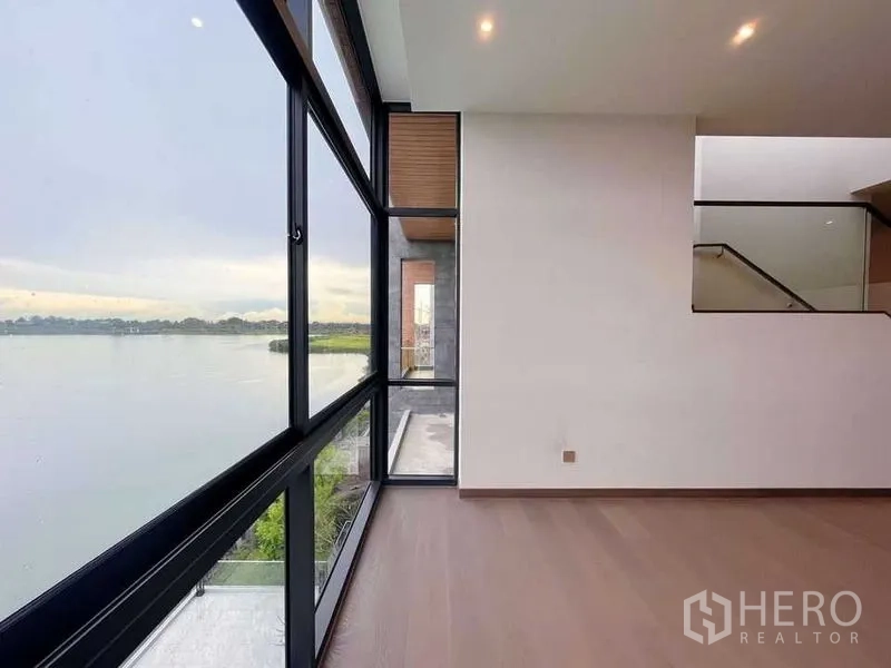 Detached House for sale in Bang Phli, Samut Prakan - Corner room with floor-to-ceiling windows providing panoramic lake views and wood flooring.