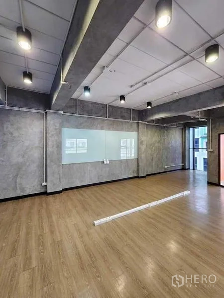 Office Space for rent or sale in Bueng Kum, Bangkok - Open-plan workspace with wood flooring, glass whiteboard, industrial ceiling lights and large window.
