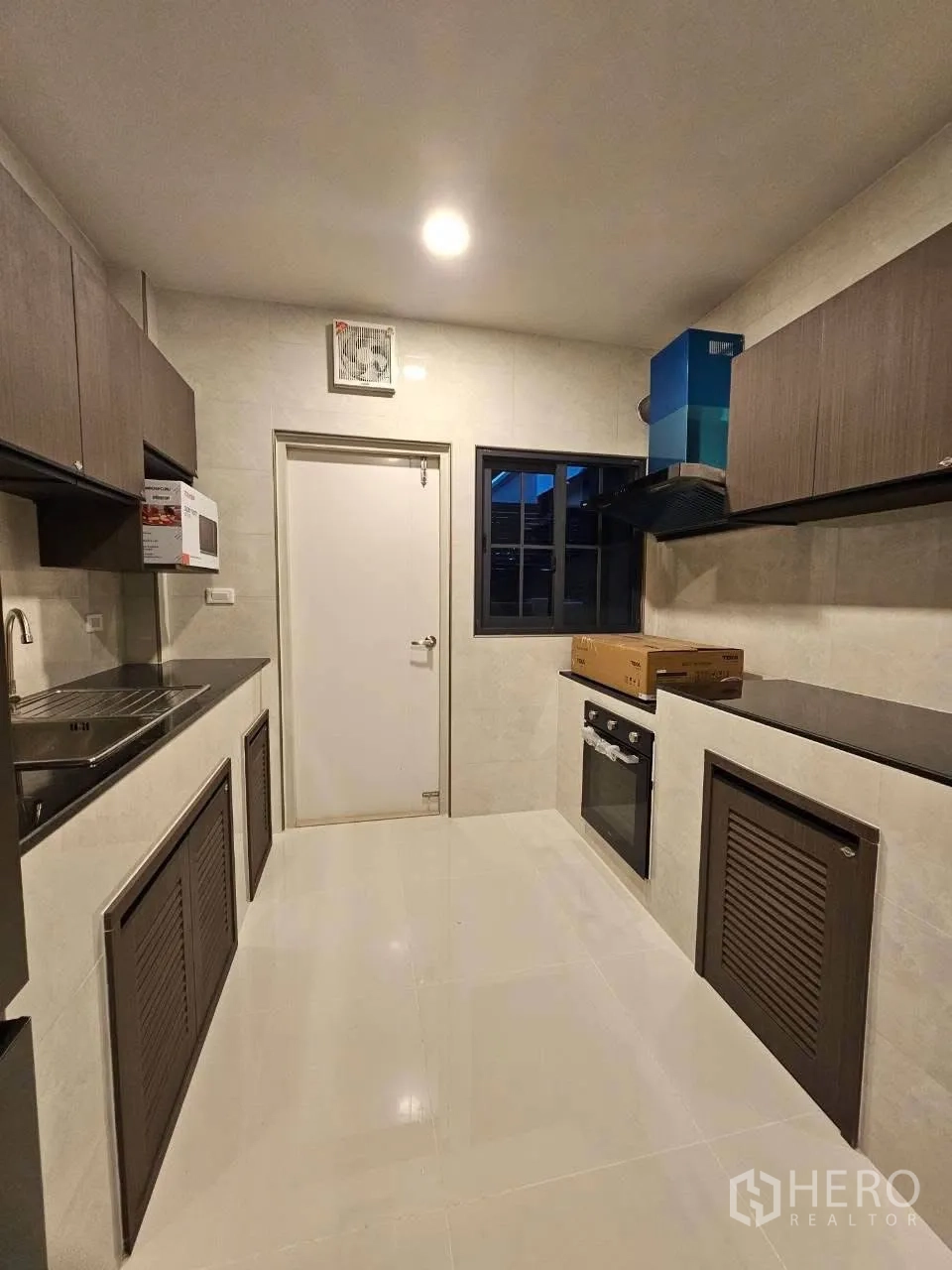 独栋房屋 for rent or sale in Bang Phli, Samut Prakan - 明亮走廊式厨房，石质台面、嵌入式烤箱与吊柜。