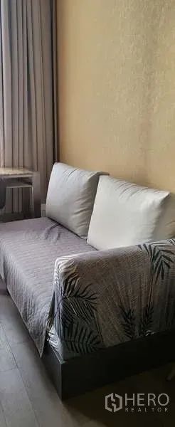 Condominium for rent - Compact sofa seating against a textured wall beside full-length curtains.