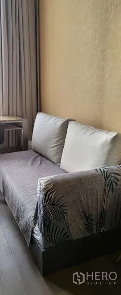 Condominium for rent - Compact sofa seating against a textured wall beside full-length curtains.