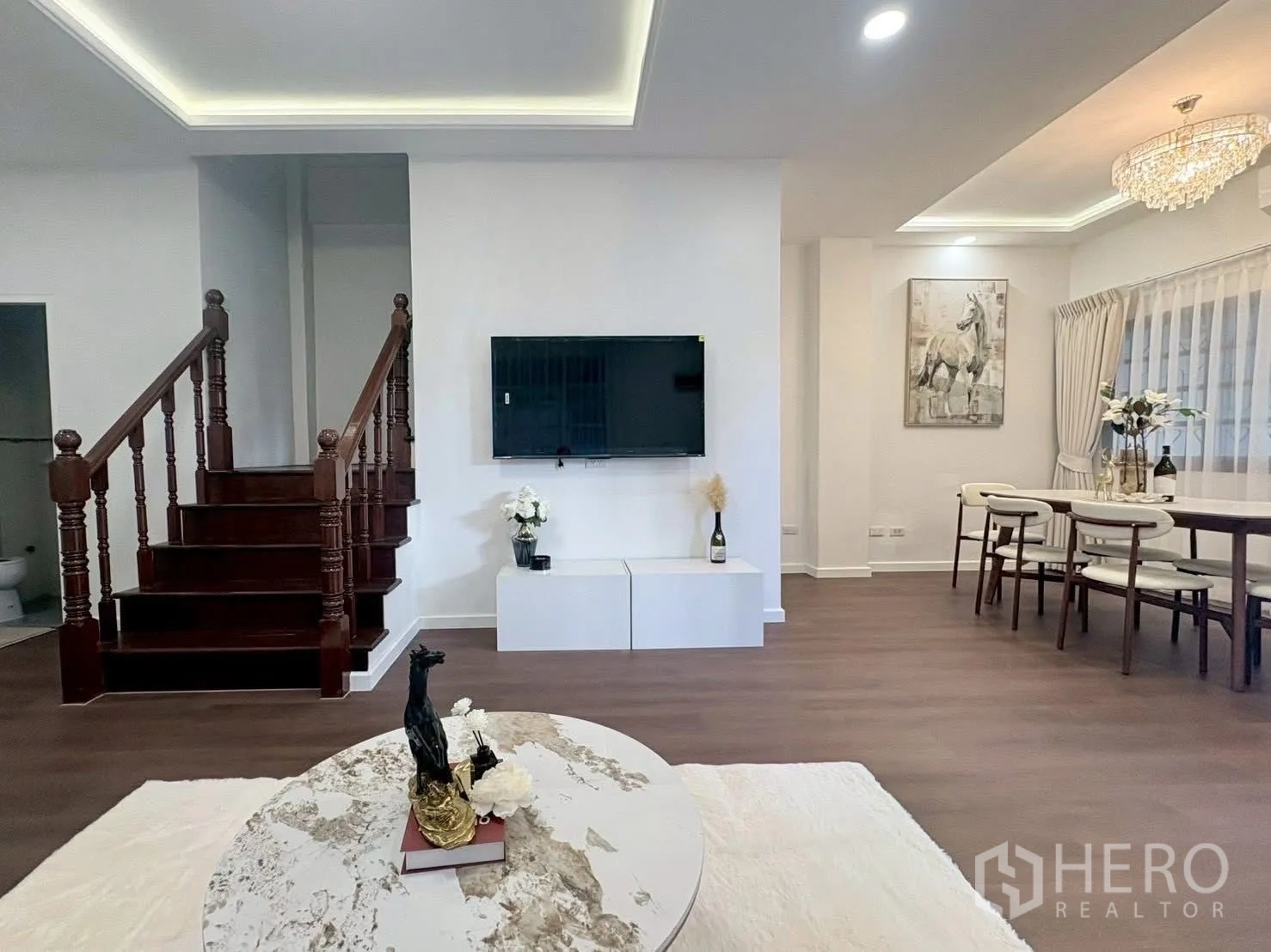 联排别墅 for rent in Huai Khwang, Bangkok - 开放式客餐厅，电视墙、吊灯与木楼梯。