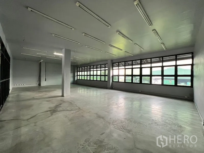 Warehouse for rent in Min Buri, Bangkok - Large upstairs office with a long row of windows and fluorescent lighting.