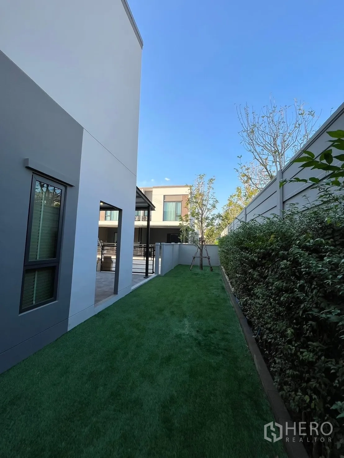 联排别墅 出租在Bang Phli, Samut Prakan - 修长的侧院草坪，隐私围栏与相邻的现代联排住宅。