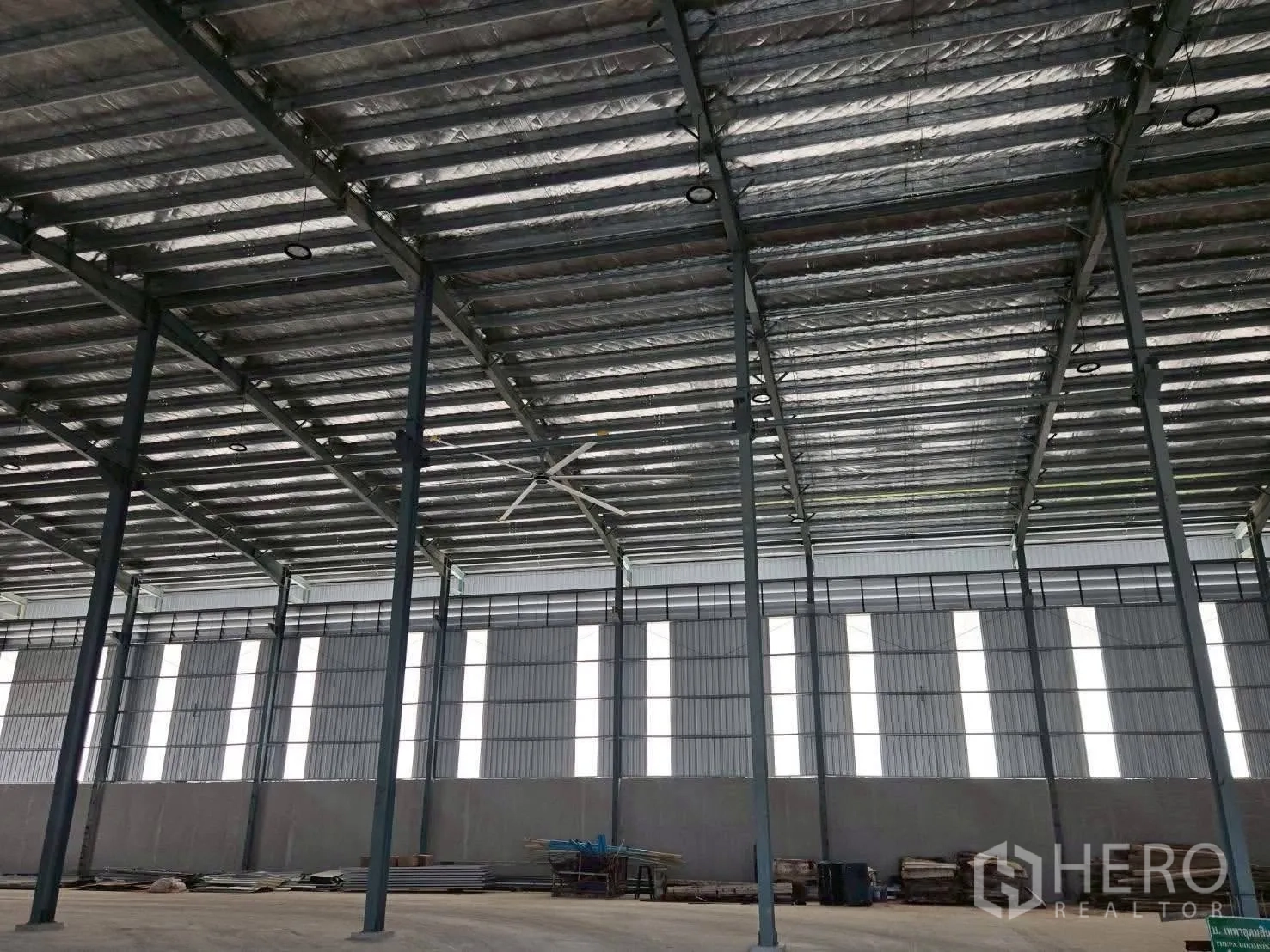 Warehouse for rent in Bang Bo, Samut Prakan - Interior roof structure with insulated panels, tall columns, and industrial fan.