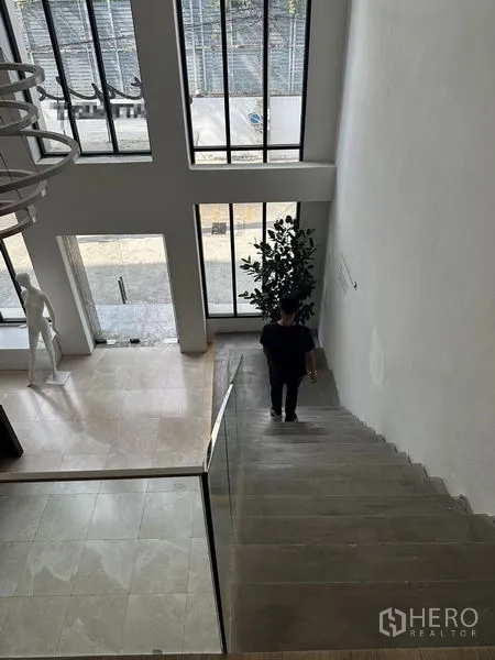 สำนักงานที่บ้าน ให้เช่าในPhra Khanong, Bangkok - มุมมองจากบันไดลงสู่โถงทางเข้าเพดานสูง ผนังกระจกเต็มบาน