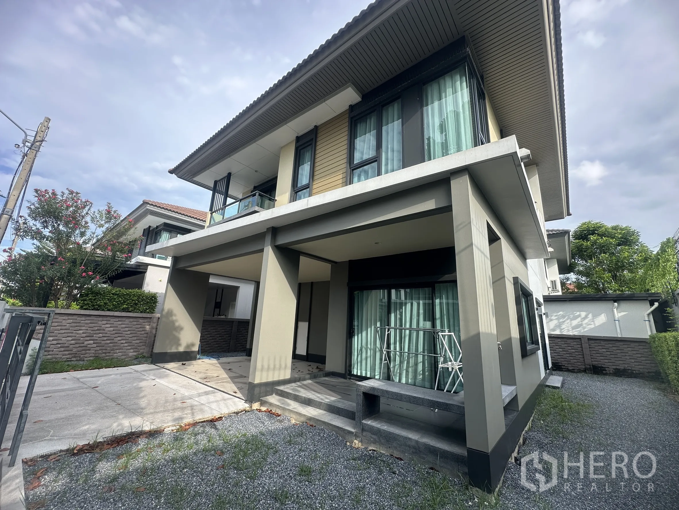 独栋房屋 for rent or sale in Lam Luk Ka, Pathum Thani - 住宅侧立面，带阳台、台阶与碎石小庭院。