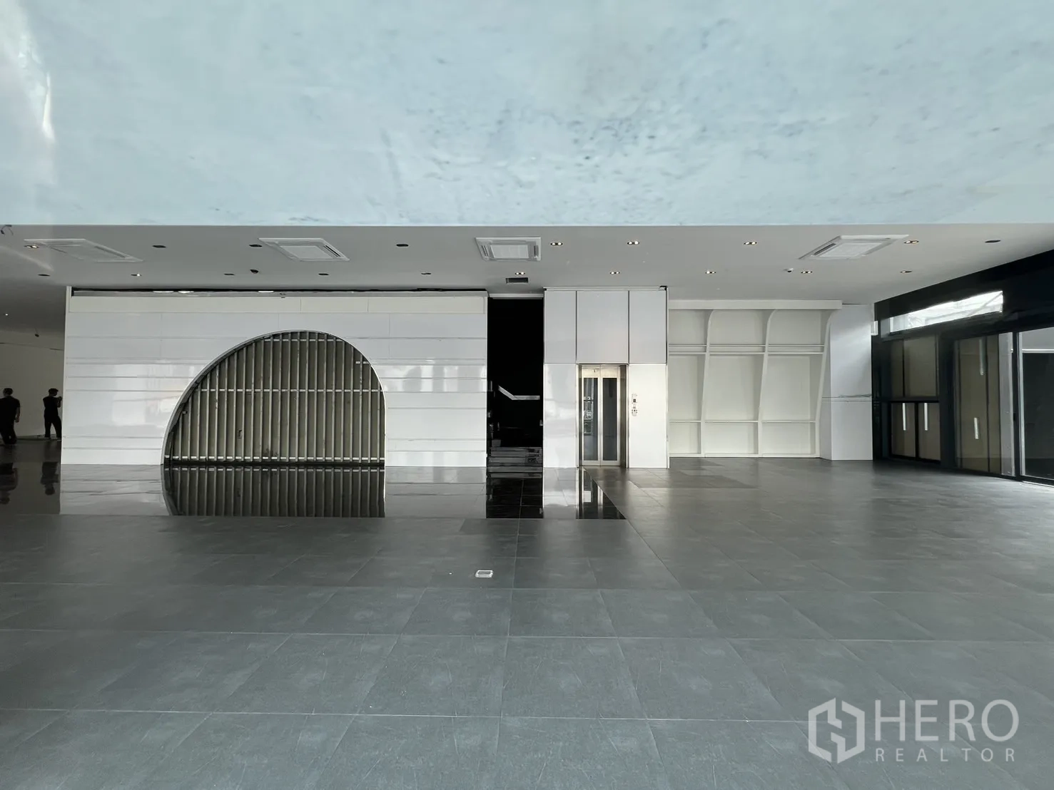 零售空间 出租在Watthana, Bangkok - 宽敞展厅区域，设有客梯、弧形装饰墙与聚光灯地面。