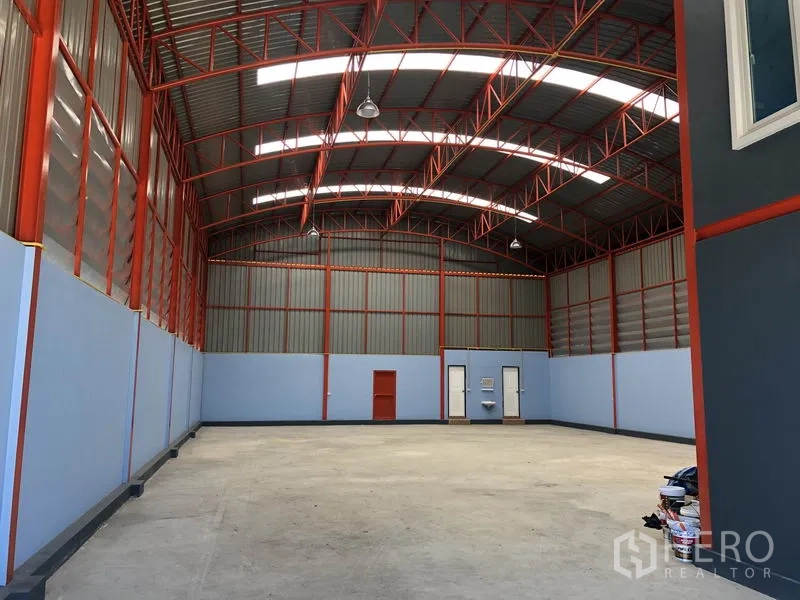货栈 出租或出售在Sai Noi, Nonthaburi - 仓库内部高挑空间，红色钢梁架与天窗，抛光混凝土地面。