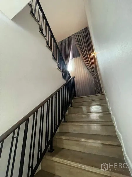 独立式住宅 出售在Bueng Kum, Bangkok - 金属扶手楼梯与高挑窗帘，通往二楼。