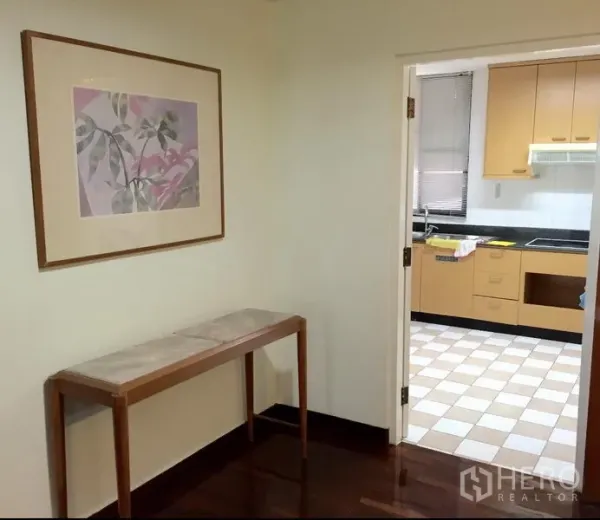 คอนโด ให้เช่าในWatthana, Bangkok - มุมทางเข้าพร้อมภาพติดผนังและโต๊ะคอนโซล เปิดสู่ห้องครัวแยก พื้นลายตารางและตู้ไม้สีอ่อน