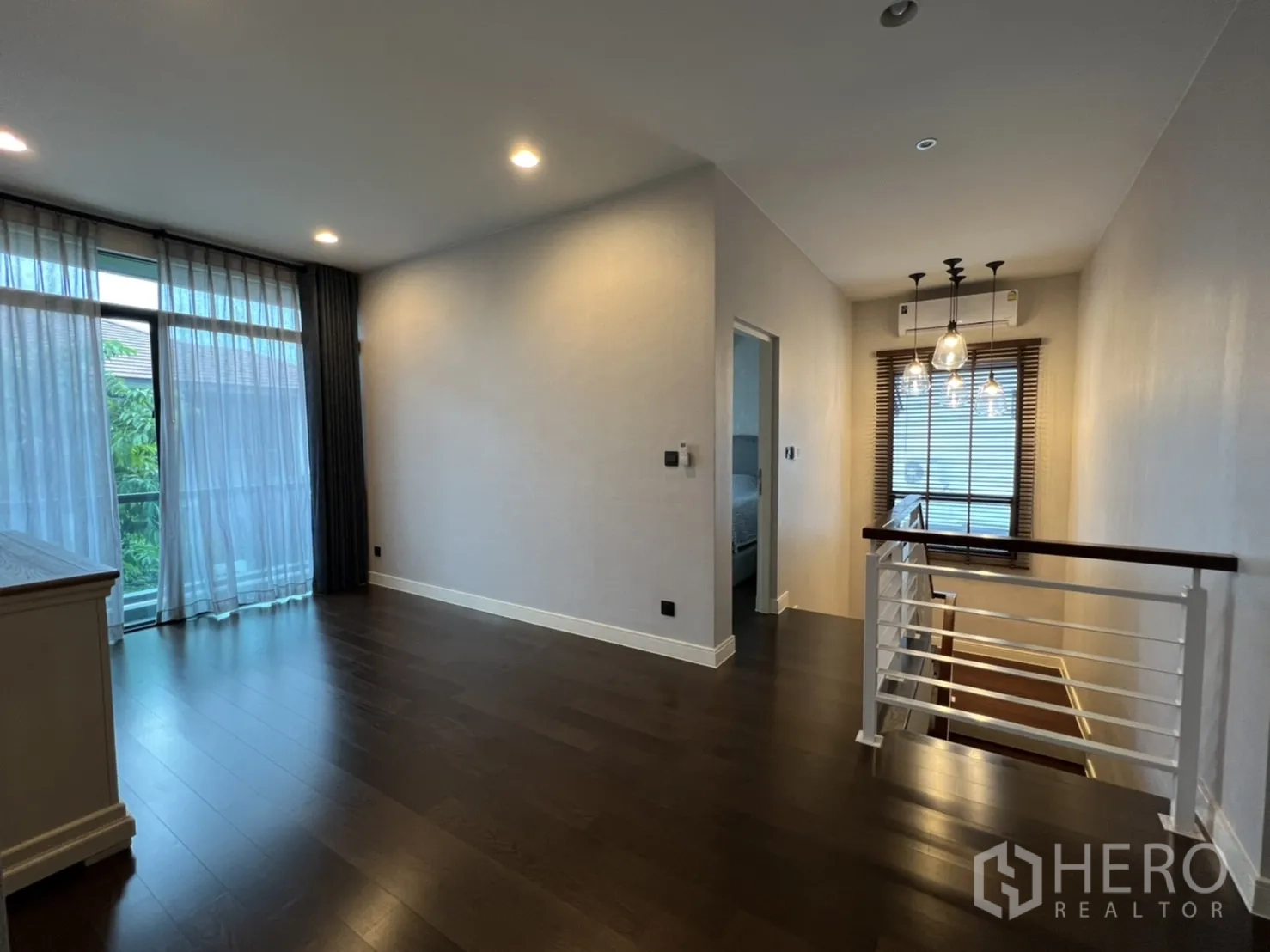 Detached House for rent or sale in Bang Kapi, Bangkok - Upstairs landing and family area with floor-to-ceiling windows and pendant lights.