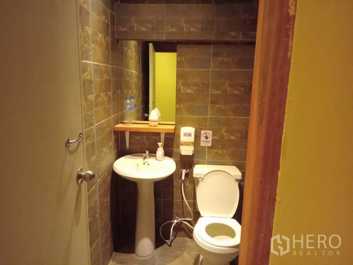 独立式住宅 出租在Phaya Thai, Bangkok - 紧凑卫生间，立式洗手盆与棕色墙砖。