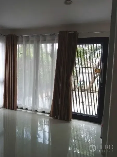 บ้าน ให้เช่าในChok Chai, Nakhon Ratchasima - ห้องนั่งเล่นสว่างพร้อมหน้าต่างกระจกเต็มบาน ผ้าม่านโปร่งและทึบ และประตูเหล็กนิรภัยมองออกสู่สวน