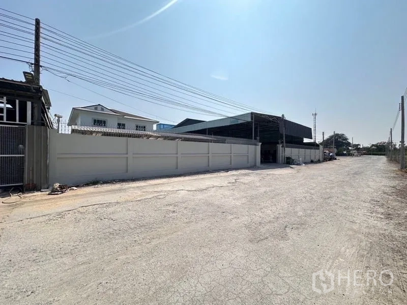 Warehouse for sale in Bang Phli, Samut Prakan - Exterior approach to the warehouse entrance and high boundary wall along a wide access road.