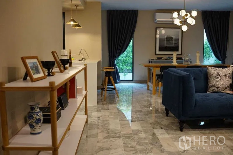 公寓 出租在Watthana, Bangkok - 宽敞开放式起居区，大理石地面、蓝色沙发与落地窗。