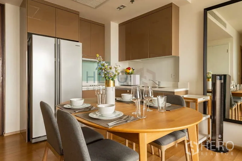 Condominium for sale in Khlong Toei, Bangkok - Kitchen with dining set, full-length mirror, and two-door refrigerator in a contemporary unit.