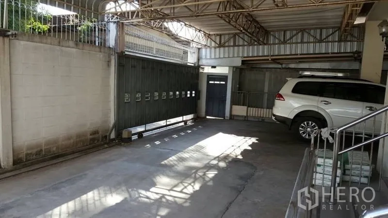 Detached House for rent in Khlong Toei, Bangkok - Covered carport with metal gate and roof truss, providing multi‑car parking.